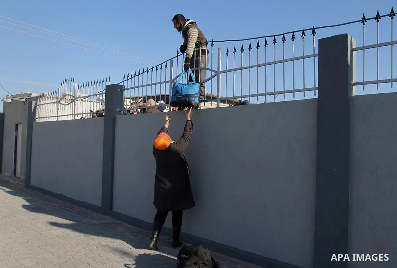 Palestinians, hoping to cross into Egypt, climb a wall as policemen loyal to Hamas stand guard at the Rafah crossing between Egypt and the southern Gaza Strip January 20, 2015. Egyptian authorities opened Rafah crossing,...
