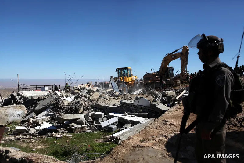 An Israeli border policeman stands guard after two houses belongings to Palestinians were demolished by the Israeli army south of the West Bank city of Hebron January 20, 2015. The owners of the house said they were info...