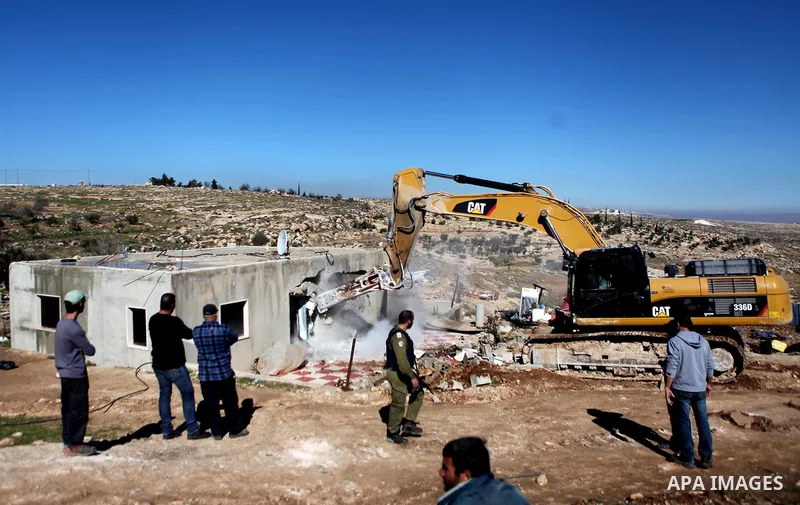An Israeli border policeman stands guard after two houses belongings to Palestinians were demolished by the Israeli army south of the West Bank city of Hebron January 20, 2015. The owners of the house said they were info...