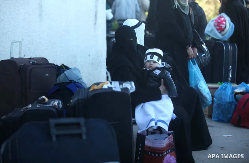 A veiled Palestinian woman, hoping to cross into Egypt, holds her child as she waits for a travel permit at the Rafah crossing between Egypt and the southern Gaza Strip January 21, 2015. Egyptian authorities opened the R...