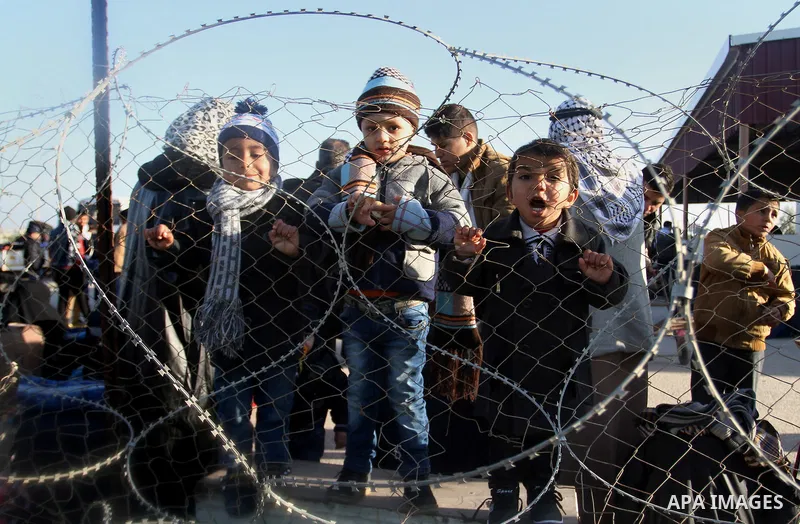 Palestinian children, hoping to cross into Egypt, stand behind a fence as they wait for a travel permit at the Rafah crossing between Egypt and the southern Gaza Strip January 22, 2015. Egyptian authorities opened the Ra...