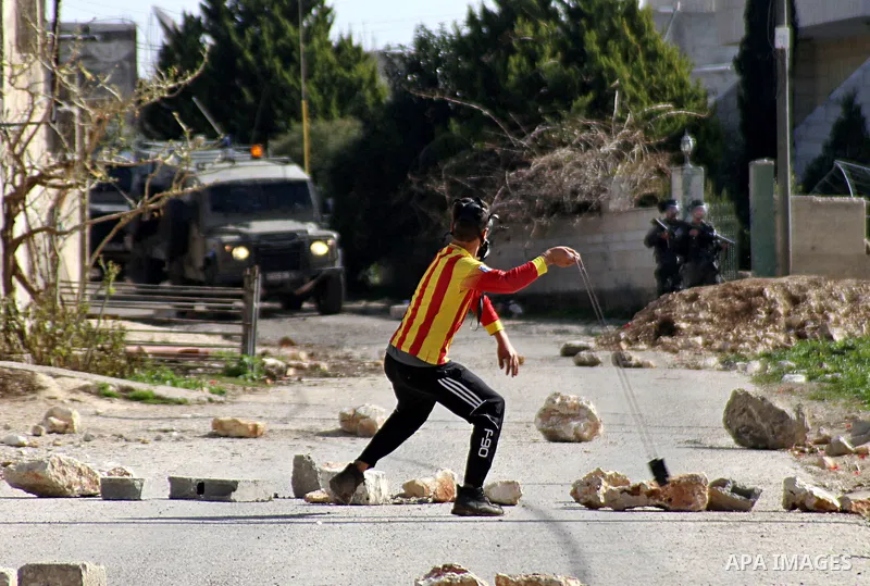 A Palestinian protester uses a slingshot to throw a stone towards Israeli security forces during clashes following a demonstration against the expropriation of Palestinian land by Israel in the village of Kfar Qaddum, ne...