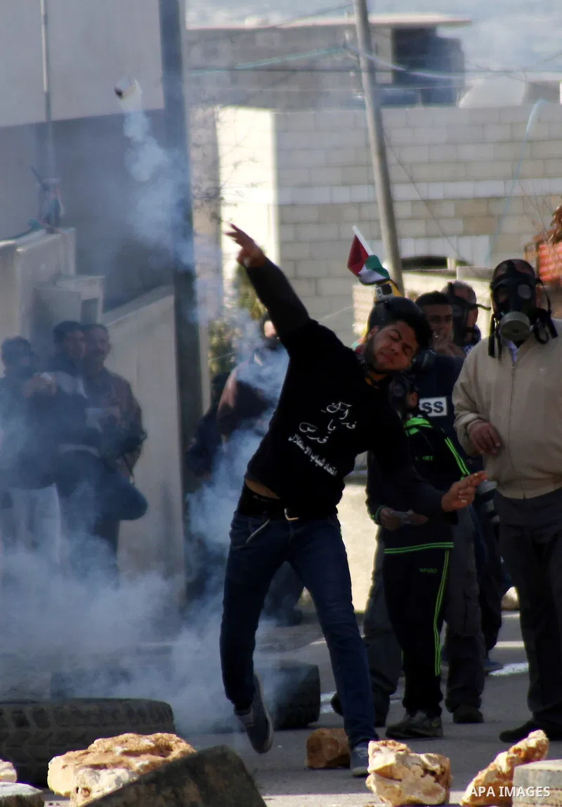 A Palestinian protester throws back a tear gas canister during clashes with Israeli security forces following a demonstration against the expropriation of Palestinian land by Israel in the village of Kfar Qaddum, near Na...