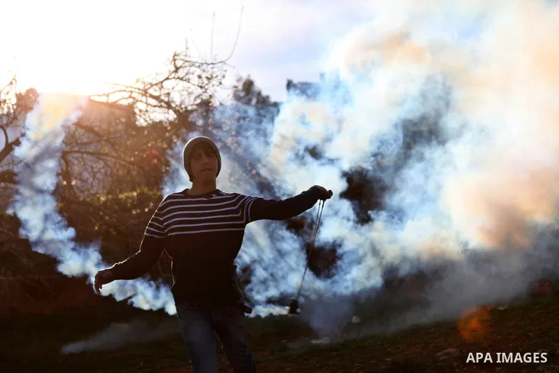 A Palestinian protester uses a slingshot to throw back a tear gas canister at Israeli security forces during clashes near Israel's Ofer prison, near the West Bank city of Ramallah January 23, 2015. Photo by Shadi Hatem