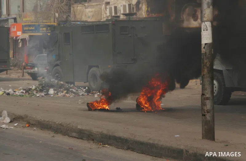 Burning tires are seen near military vehicles in Mataryah destrict, in Cairo on January 25, 2015. A protester was killed in Egypt and a bomb wounded two policemen on Sunday, the anniversary of the 2011 uprising that topp...