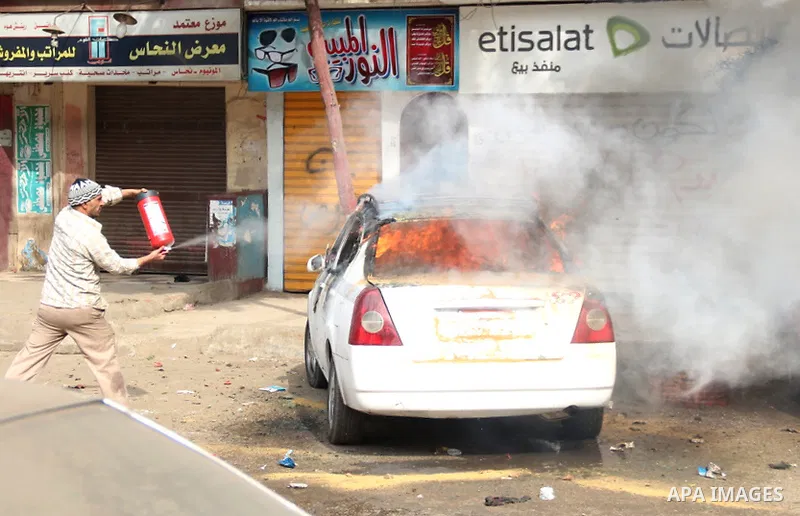 An Egyptian man tries to extinguish the fire in a car in Mataryah destrict, in Cairo on January 25, 2015. A protester was killed in Egypt and a bomb wounded two policemen on Sunday, the anniversary of the 2011 uprising t...