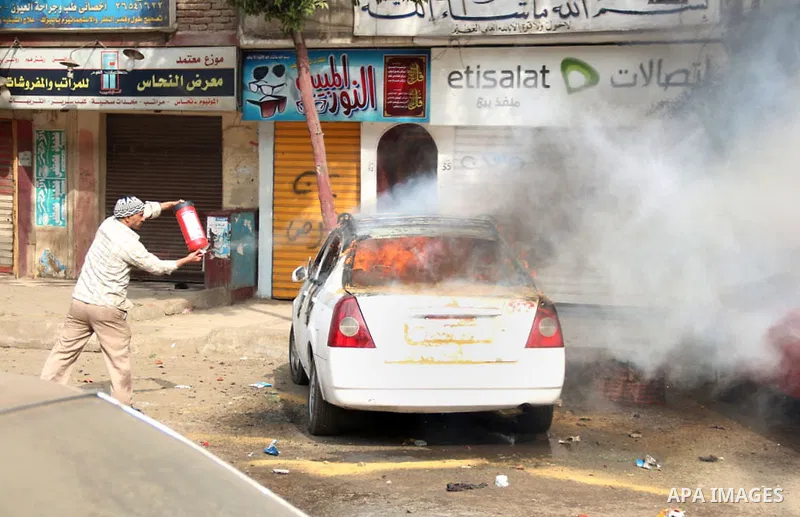An Egyptian man tries to extinguish the fire in a car in Mataryah destrict, in Cairo on January 25, 2015. A protester was killed in Egypt and a bomb wounded two policemen on Sunday, the anniversary of the 2011 uprising t...
