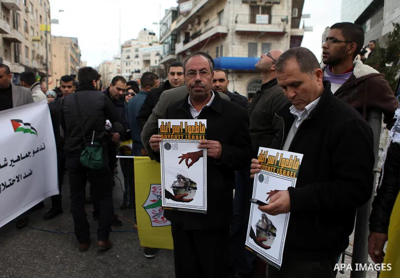 Palestinians hold placards during a rally organised by Fatah movement to support President Mahmoud Abbas' policy and calling to boycott Israeli goods, in the West Bank city of Ramallah, January 26, 2015. Photo by Shadi H...