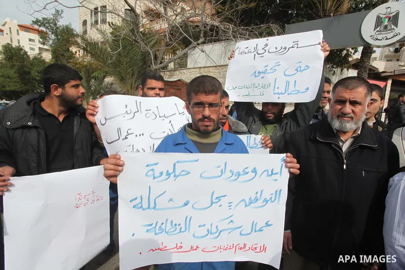 Palestinian cleaning workers hold banners during a protest calling the government for pay their salaries, in front of the headquarters of the Council of Ministers in Gaza city on January 27, 2015. Some 40,000 civil serva...