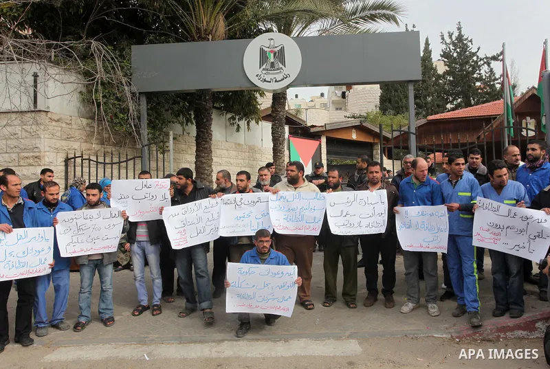 Palestinian cleaning workers hold banners during a protest calling the government for pay their salaries, in front of the headquarters of the Council of Ministers in Gaza city on January 27, 2015. Some 40,000 civil serva...