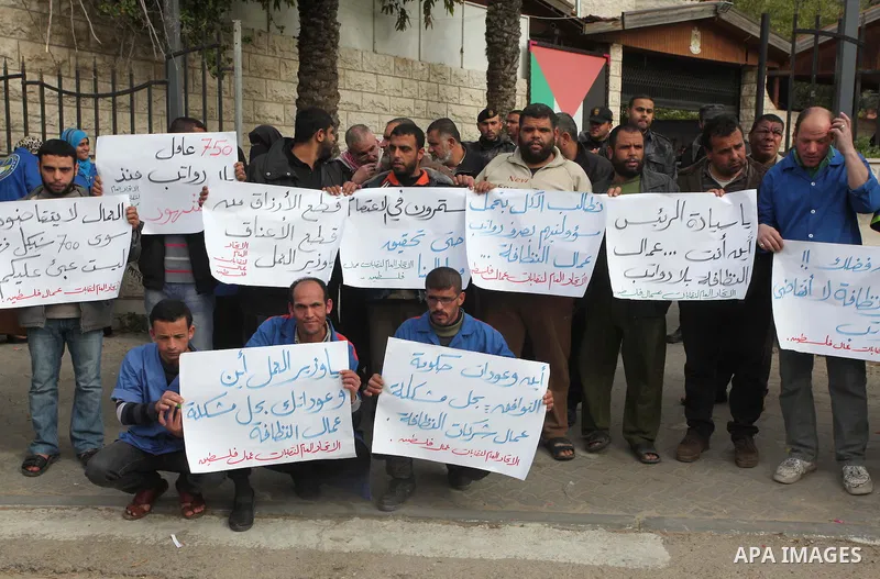 Palestinian cleaning workers hold banners during a protest calling the government for pay their salaries, in front of the headquarters of the Council of Ministers in Gaza city on January 27, 2015. Some 40,000 civil serva...