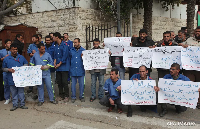 Palestinian cleaning workers hold banners during a protest calling the government for pay their salaries, in front of the headquarters of the Council of Ministers in Gaza city on January 27, 2015. Some 40,000 civil serva...