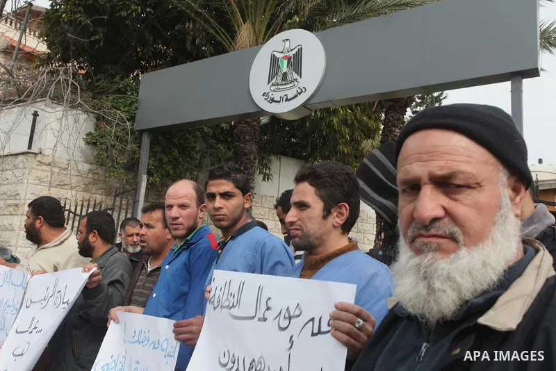 Palestinian cleaning workers hold banners during a protest calling the government for pay their salaries, in front of the headquarters of the Council of Ministers in Gaza city on January 27, 2015. Some 40,000 civil serva...