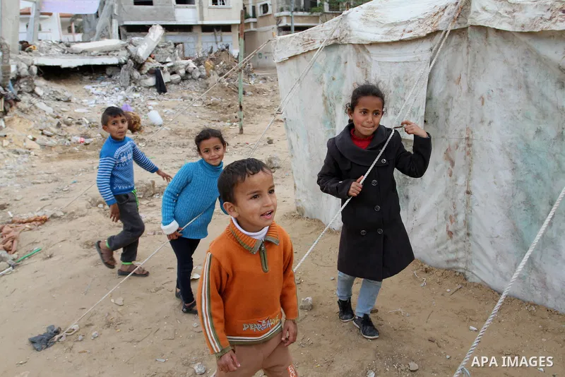 Palestinian children play outside tents near the ruins of their houses which witnesses said were destroyed by Israel shelling during a 50-day conflict last summer, east of Khan Younis in the southern Gaza Strip January 2...
