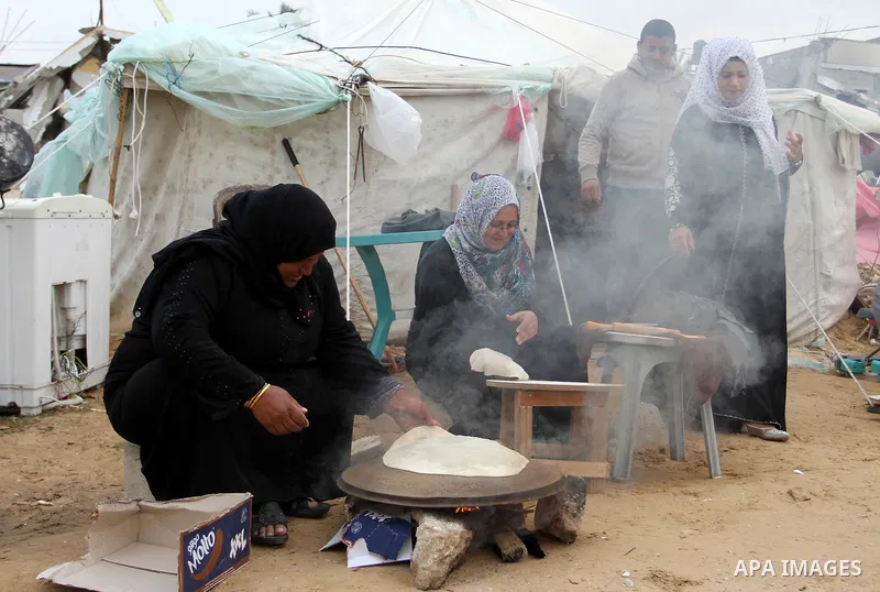 Palestinian women bake bread on firewood outside a tent near the ruins of their houses which witnesses said were destroyed by Israel shelling during a 50-day conflict last summer, east of Khan Younis in the southern Gaza...