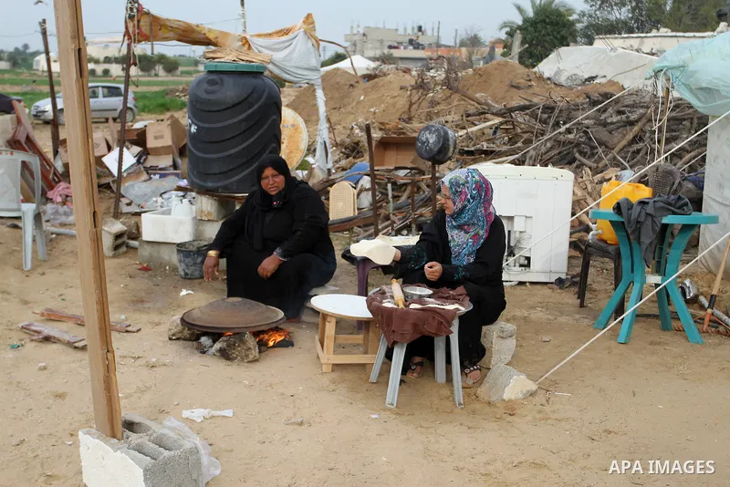 Palestinian women bake bread on firewood outside a tent near the ruins of their houses which witnesses said were destroyed by Israel shelling during a 50-day conflict last summer, east of Khan Younis in the southern Gaza...