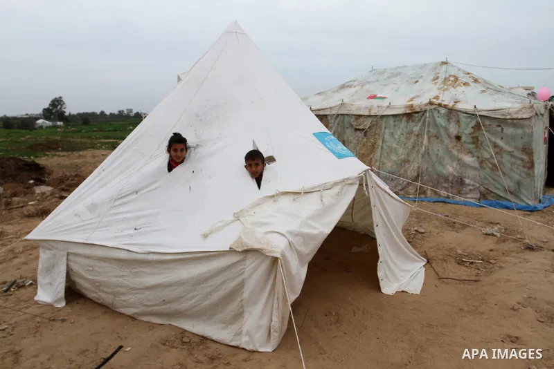 Palestinian children play at a tent near the ruins of their family's house which witnesses said were destroyed by Israel shelling during a 50-day conflict last summer, east of Khan Younis in the southern Gaza Strip Janua...