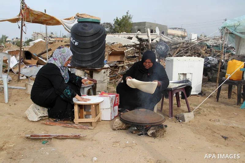Palestinian women bake bread on firewood outside a tent near the ruins of their houses which witnesses said were destroyed by Israel shelling during a 50-day conflict last summer, east of Khan Younis in the southern Gaza...