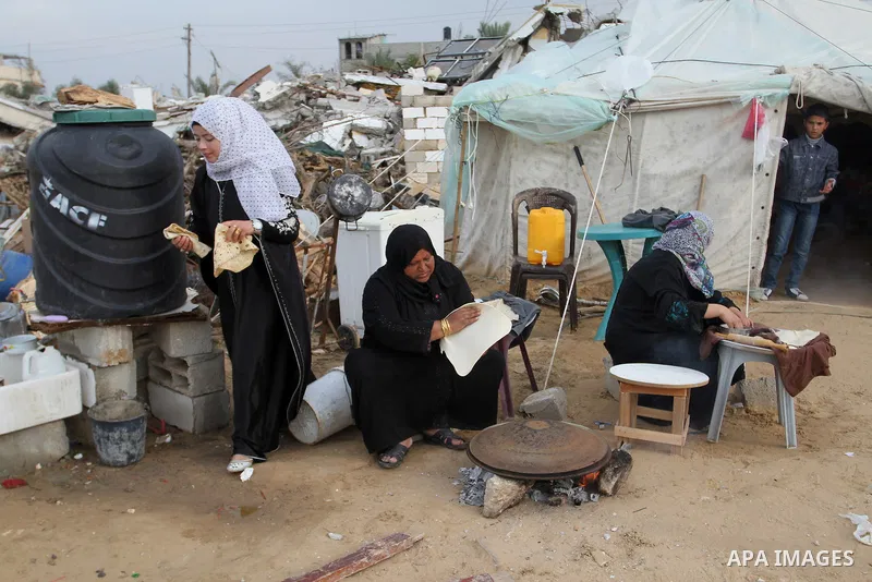 Palestinian women bake bread on firewood outside a tent near the ruins of their houses which witnesses said were destroyed by Israel shelling during a 50-day conflict last summer, east of Khan Younis in the southern Gaza...
