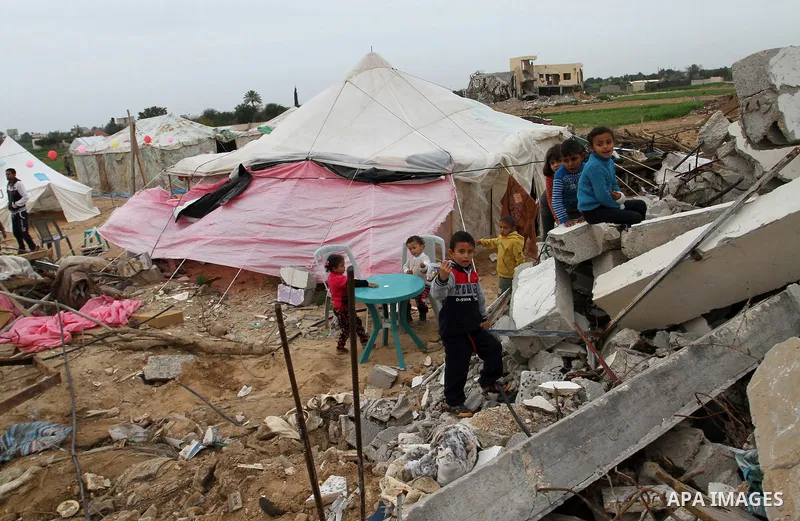 Palestinian children play outside tents near the ruins of their houses which witnesses said were destroyed by Israel shelling during a 50-day conflict last summer, east of Khan Younis in the southern Gaza Strip January 2...