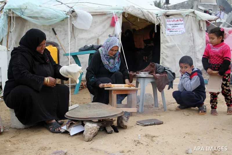 Palestinian women bake bread on firewood outside a tent near the ruins of their houses which witnesses said were destroyed by Israel shelling during a 50-day conflict last summer, east of Khan Younis in the southern Gaza...