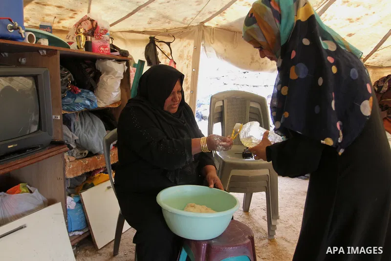 A Palestinian woman prepares the dough to bake bread at a tent near the ruins of her house which witnesses said were destroyed by Israel shelling during a 50-day conflict last summer, east of Khan Younis in the southern...