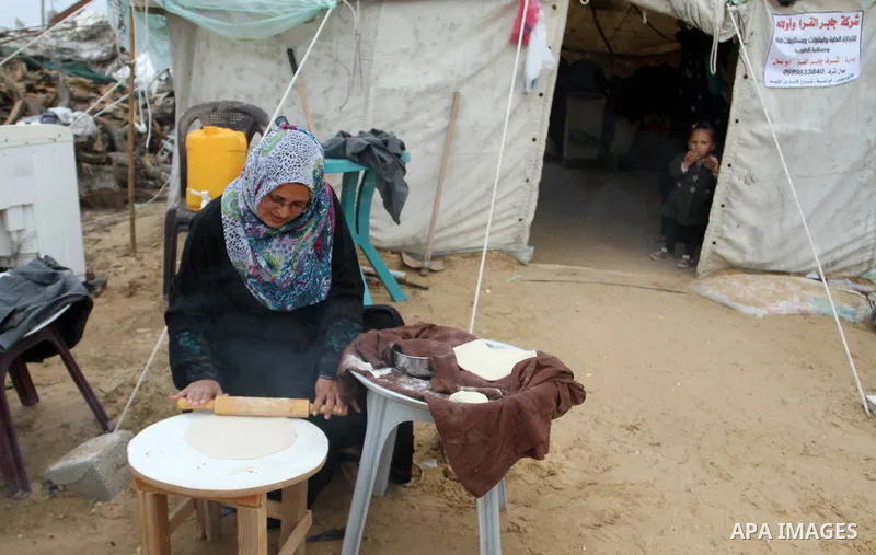 Palestinian women bake bread on firewood outside a tent near the ruins of their houses which witnesses said were destroyed by Israel shelling during a 50-day conflict last summer, east of Khan Younis in the southern Gaza...