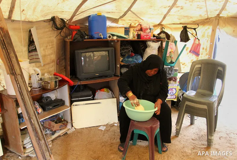 A Palestinian woman prepares the dough to bake bread at a tent near the ruins of her house which witnesses said were destroyed by Israel shelling during a 50-day conflict last summer, east of Khan Younis in the southern...