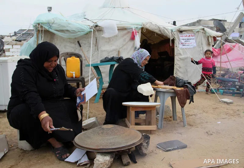 Palestinian women bake bread on firewood outside a tent near the ruins of their houses which witnesses said were destroyed by Israel shelling during a 50-day conflict last summer, east of Khan Younis in the southern Gaza...