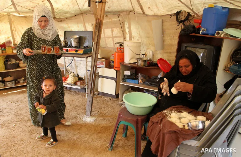 A Palestinian woman prepares the dough to bake bread at a tent near the ruins of her house which witnesses said were destroyed by Israel shelling during a 50-day conflict last summer, east of Khan Younis in the southern...