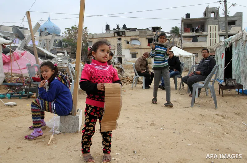 Palestinian children play outside tents near the ruins of their houses which witnesses said were destroyed by Israel shelling during a 50-day conflict last summer, east of Khan Younis in the southern Gaza Strip January 2...