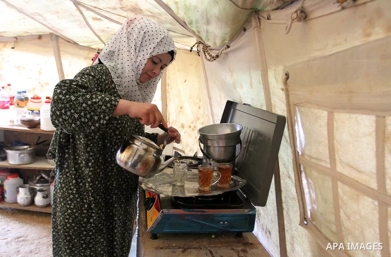 A Palestinian woman prepares tea at a tent near the ruins of her house which witnesses said were destroyed by Israel shelling during a 50-day conflict last summer, east of Khan Younis in the southern Gaza Strip January 2...