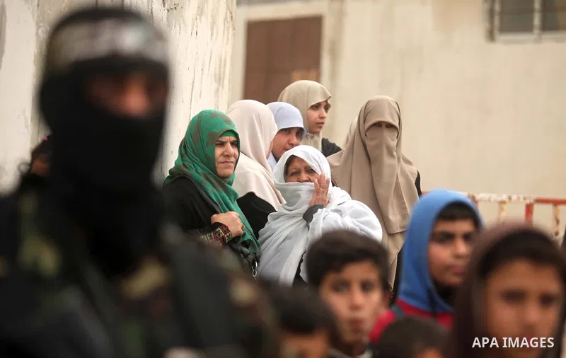 Palestinians look at members of Ezz Eddin al-Qassam brigades hold weapons as they march during a protest rally in support of the Prophet Mohammed in Gaza City on January 27, 2015. Photo by Ashraf Amra