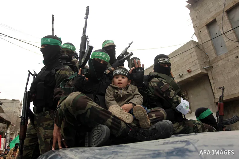 Palestinian members of Ezz Eddin al-Qassam brigades hold weapons as they march during a protest rally in support of the Prophet Mohammed in Gaza City on January 27, 2015. Photo by Ashraf Amra