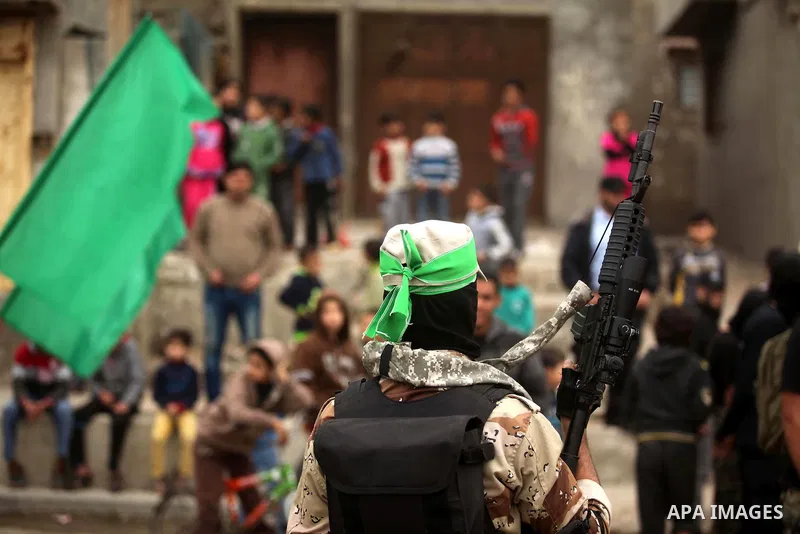 Palestinians look at members of Ezz Eddin al-Qassam brigades hold weapons as they march during a protest rally in support of the Prophet Mohammed in Gaza City on January 27, 2015. Photo by Ashraf Amra