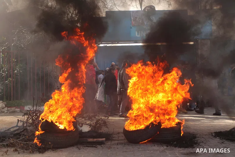 Palestinians burn tires during a protest against the decision by the main U.N. aid agency to suspend payments to tens of thousands of Palestinians for repairs to their homes damaged in last summer's war, outside the head...