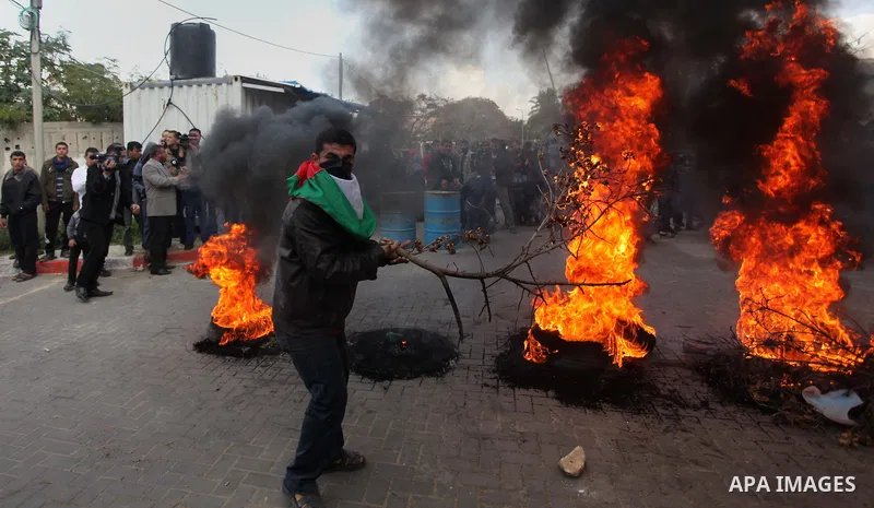Palestinians burn tires during a protest against the decision by the main U.N. aid agency to suspend payments to tens of thousands of Palestinians for repairs to their homes damaged in last summer's war, outside the head...