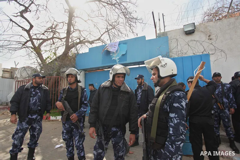 Palestinian policemen stand guard a protest against the decision by the main U.N. aid agency to suspend payments to tens of thousands of Palestinians for repairs to their homes damaged in last summer's war, outside the h...