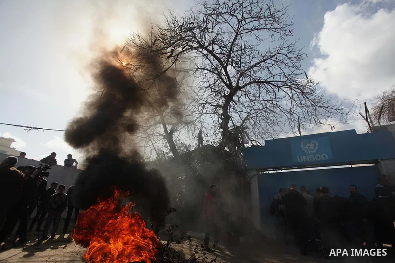 Palestinians burn tires during a protest against the decision by the main U.N. aid agency to suspend payments to tens of thousands of Palestinians for repairs to their homes damaged in last summer's war, outside the head...