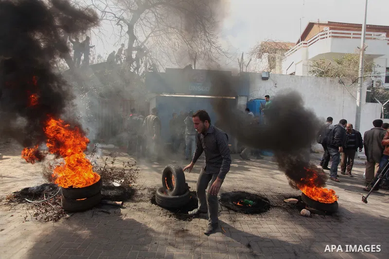 Palestinians burn tires during a protest against the decision by the main U.N. aid agency to suspend payments to tens of thousands of Palestinians for repairs to their homes damaged in last summer's war, outside the head...