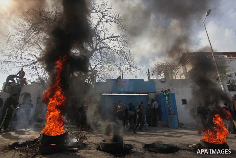 Palestinians burn tires during a protest against the decision by the main U.N. aid agency to suspend payments to tens of thousands of Palestinians for repairs to their homes damaged in last summer's war, outside the head...