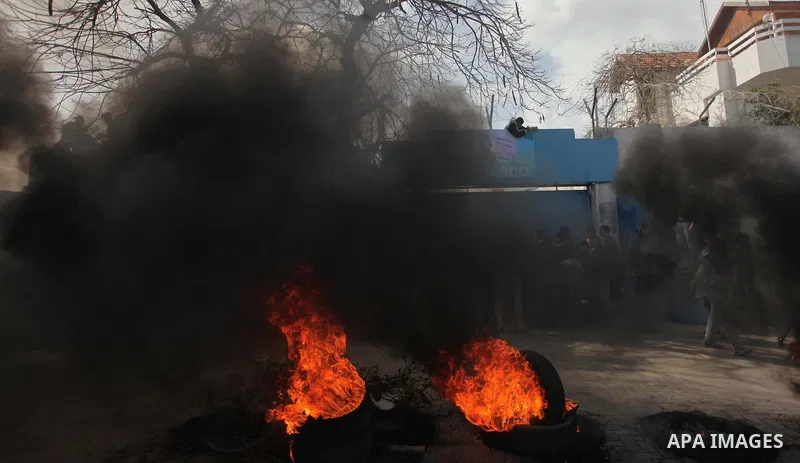 Palestinians burn tires during a protest against the decision by the main U.N. aid agency to suspend payments to tens of thousands of Palestinians for repairs to their homes damaged in last summer's war, outside the head...