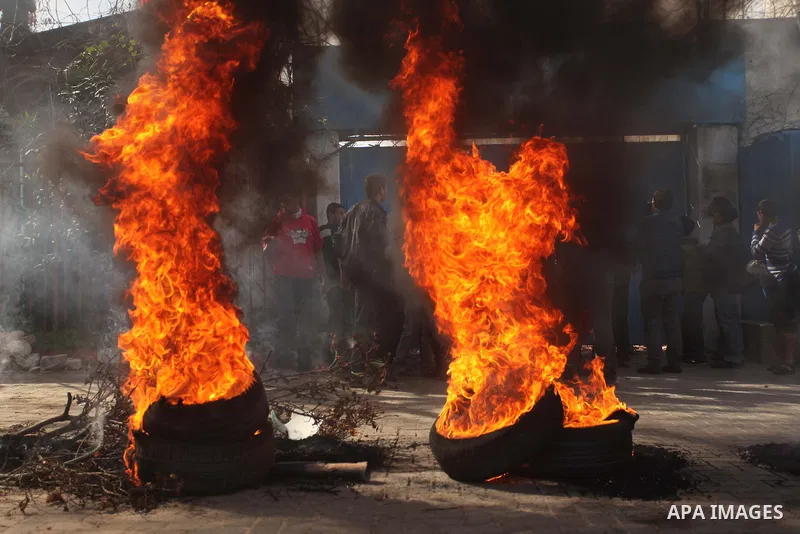 Palestinians burn tires during a protest against the decision by the main U.N. aid agency to suspend payments to tens of thousands of Palestinians for repairs to their homes damaged in last summer's war, outside the head...