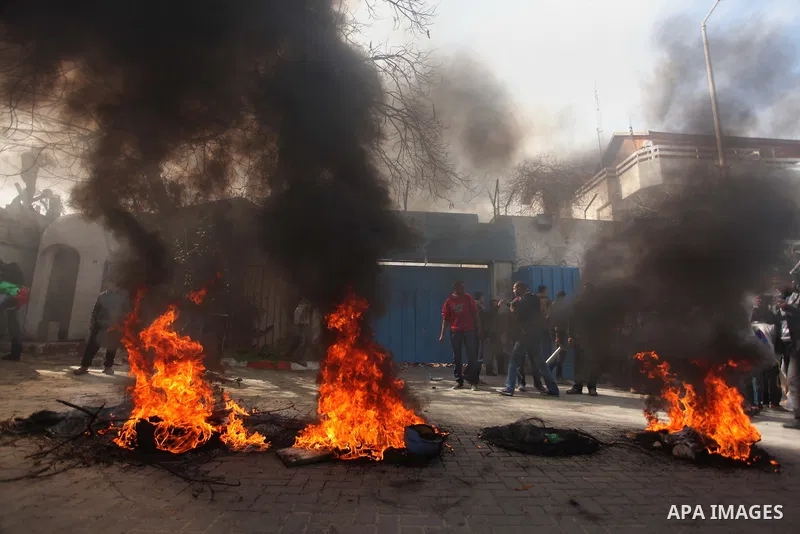 Palestinians burn tires during a protest against the decision by the main U.N. aid agency to suspend payments to tens of thousands of Palestinians for repairs to their homes damaged in last summer's war, outside the head...