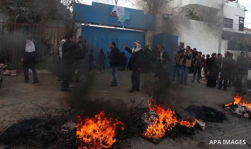Palestinians burn tires during a protest against the decision by the main U.N. aid agency to suspend payments to tens of thousands of Palestinians for repairs to their homes damaged in last summer's war, outside the head...