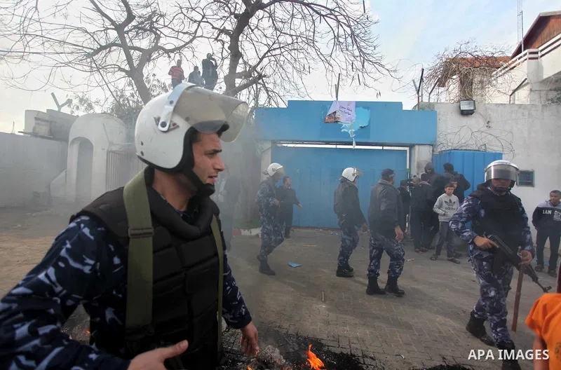Palestinian policemen stand guard a protest against the decision by the main U.N. aid agency to suspend payments to tens of thousands of Palestinians for repairs to their homes damaged in last summer's war, outside the h...