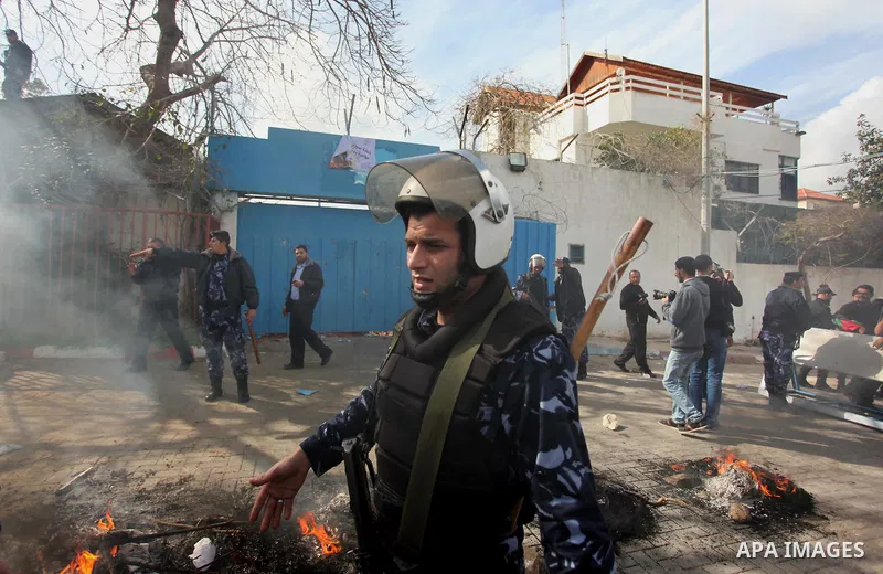 Palestinian policemen stand guard a protest against the decision by the main U.N. aid agency to suspend payments to tens of thousands of Palestinians for repairs to their homes damaged in last summer's war, outside the h...