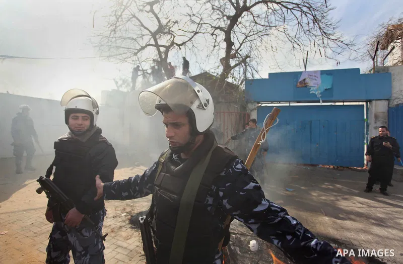Palestinian policemen stand guard a protest against the decision by the main U.N. aid agency to suspend payments to tens of thousands of Palestinians for repairs to their homes damaged in last summer's war, outside the h...