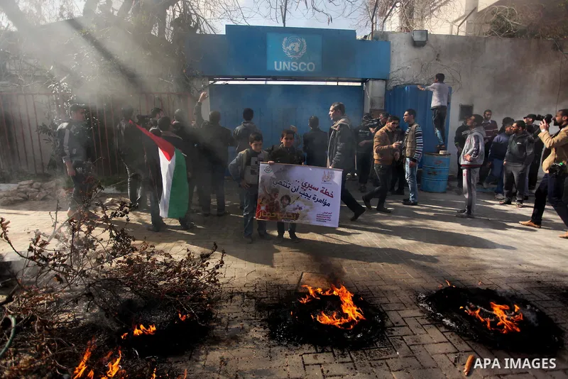 Palestinians burn tires during a protest against the decision by the main U.N. aid agency to suspend payments to tens of thousands of Palestinians for repairs to their homes damaged in last summer's war, outside the head...