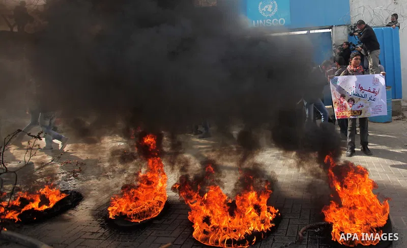 Palestinians burn tires during a protest against the decision by the main U.N. aid agency to suspend payments to tens of thousands of Palestinians for repairs to their homes damaged in last summer's war, outside the head...